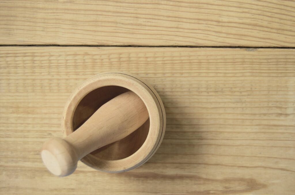 Top view of a wooden mortar and pestle on a rustic wooden surface. Ideal for kitchen or culinary themes.